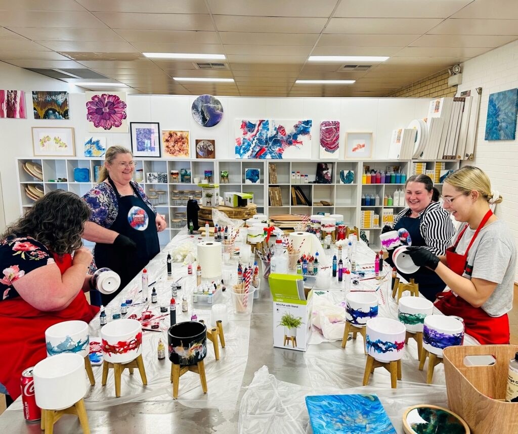 Pot painting workshop among the studio's art walls and supplies
