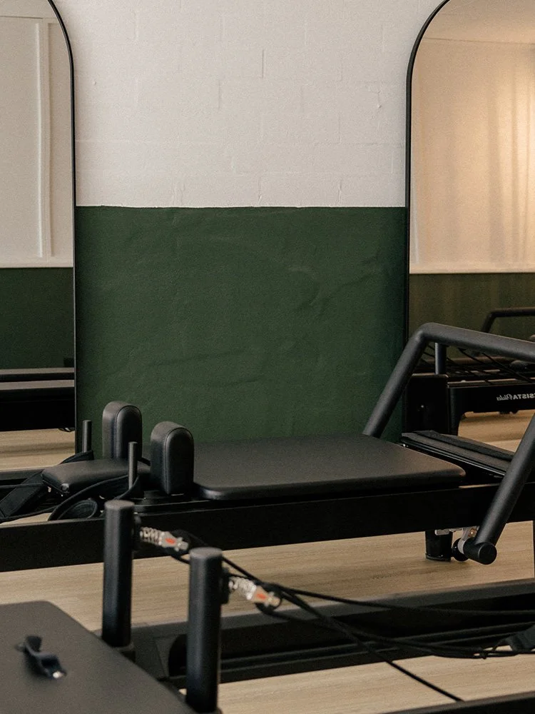 Reformer beds against the studio's signature green wall